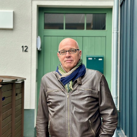 Ein Mann steht vor einer grünen Tür.