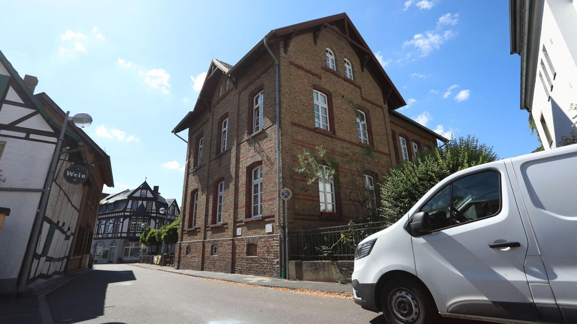 Ein altes Backsteingebäude, davor fährt ein weißer Lieferwagen über die Straße.
