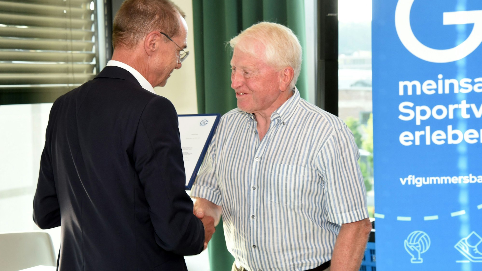 Bild einer Ehrung eines Mannes durch einen anderen Mann