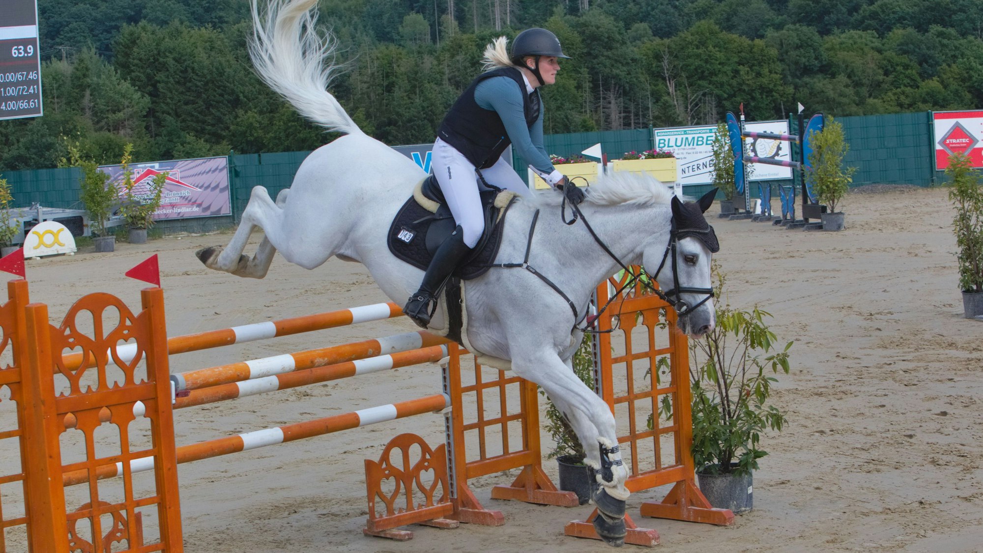 Zu sehen ist eine Frau, die mit ihrem Pferd über ein Hindernis springt.