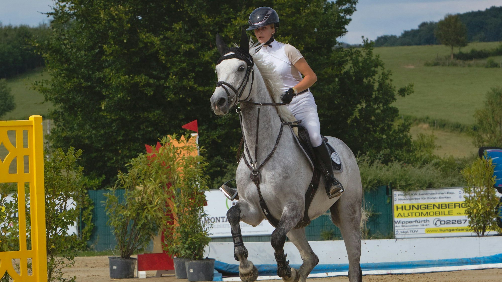 Zu sehen ist eine Frau, die mit ihrem Pferd über ein Hindernis springt.