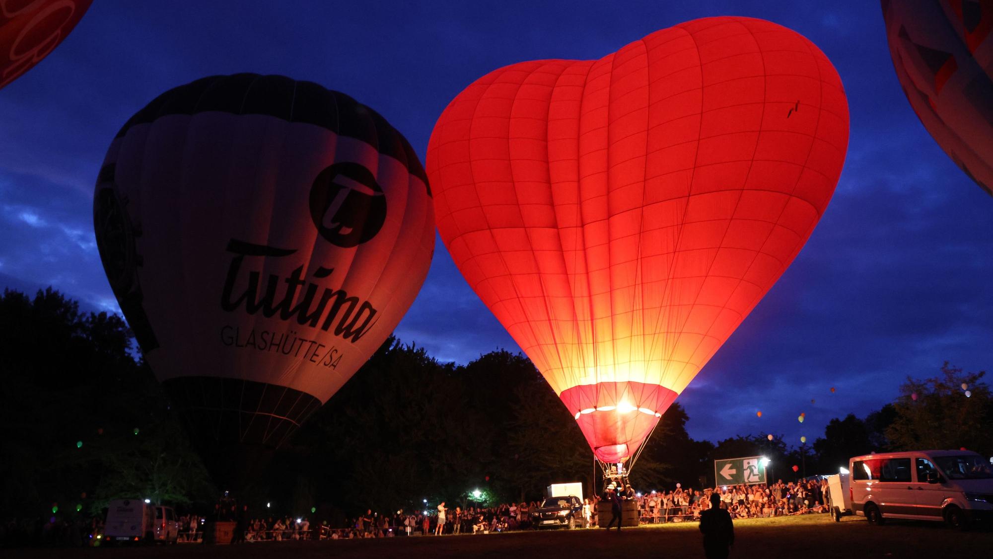 Ein herzförmiger Heißluftballon glüht rot im Dunkeln.