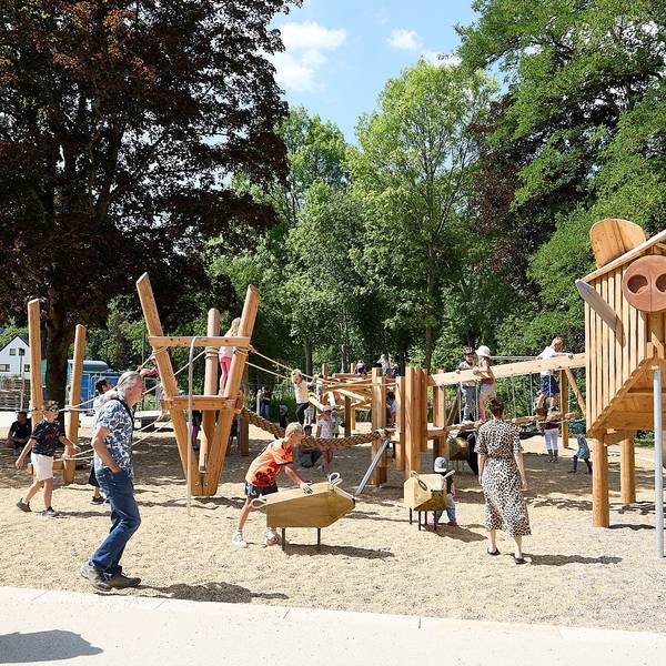 Kinder spielen auf dem neuen Spielplatz im Kurpark in Gemünd. Die Spielgeräte sind aus Holz gestaltet.