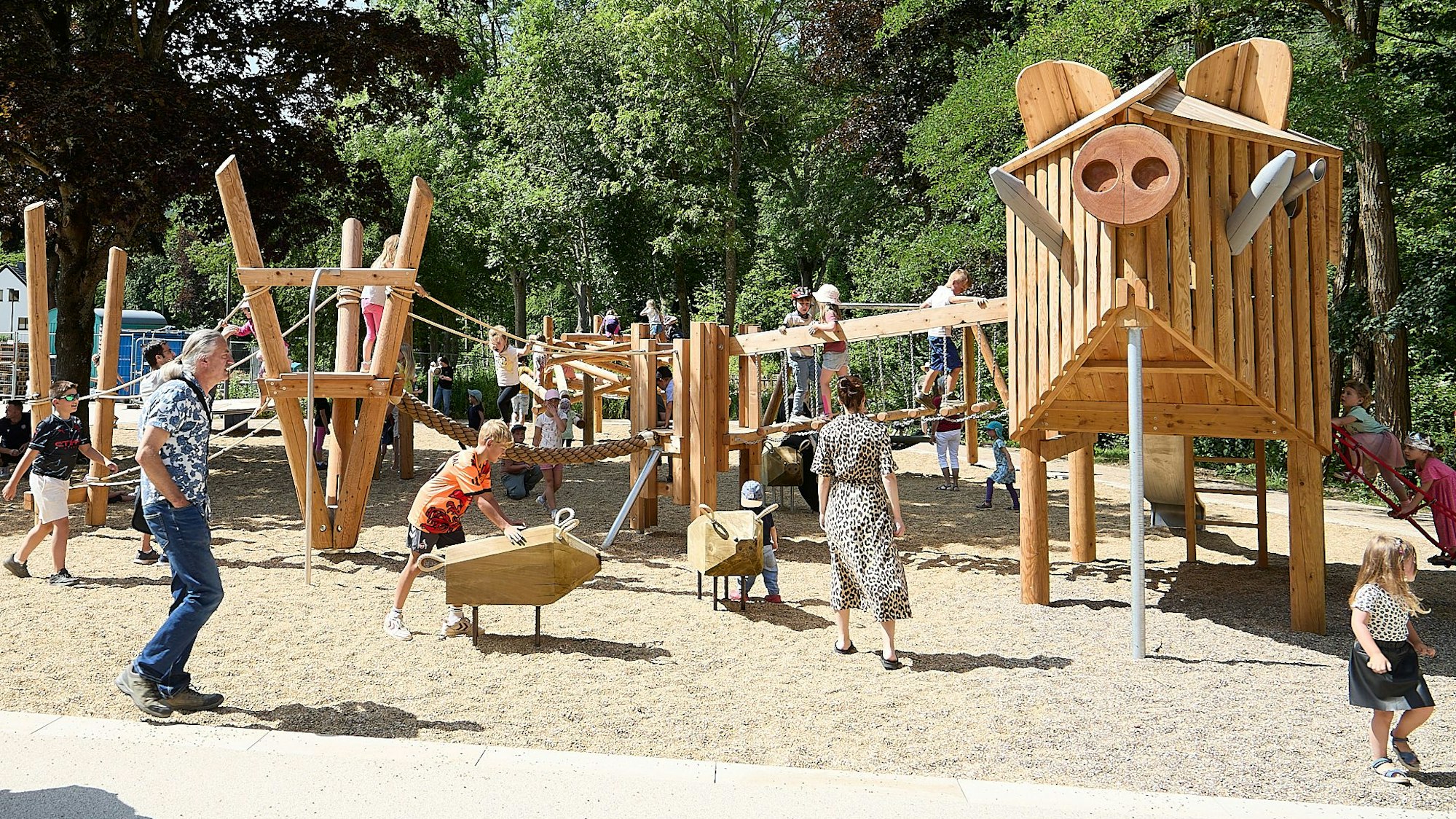 Kinder spielen auf dem neuen Spielplatz im Kurpark in Gemünd. Die Spielgeräte sind aus Holz gestaltet.