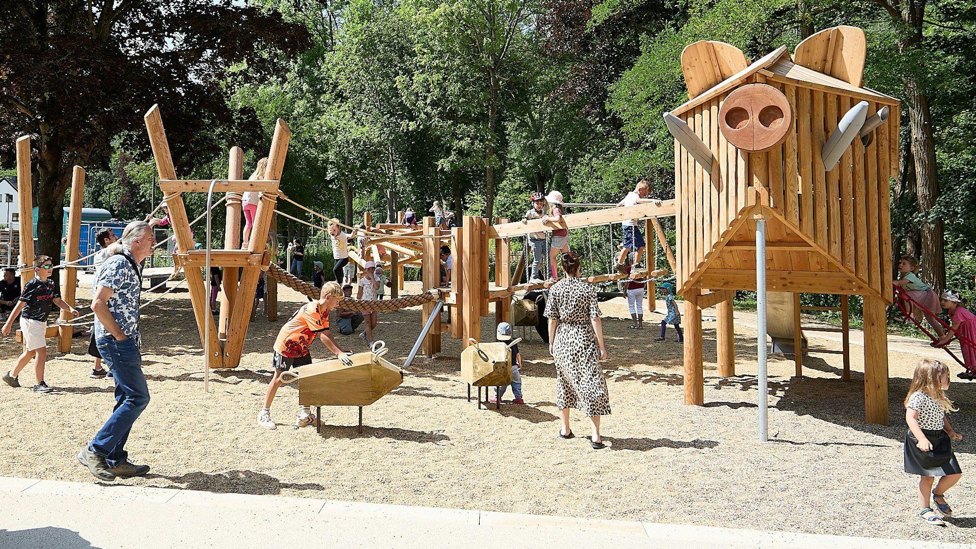 Kinder spielen auf dem neuen Spielplatz im Kurpark in Gemünd. Die Spielgeräte sind aus Holz gestaltet.