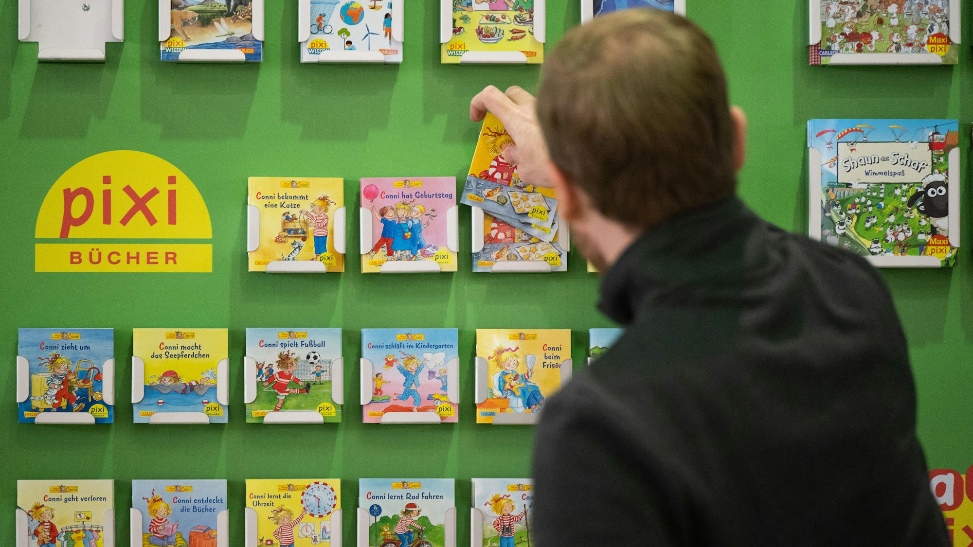 ARCHIV - 18.10.2021, Hessen, Frankfurt/Main: Ein Mann räumt Conni Kinderbücher in ein Regal (zu dpa: «Carlsen Verlag erklärt Umgang mit Conni-Memes») Foto: Sebastian Gollnow/dpa +++ dpa-Bildfunk +++