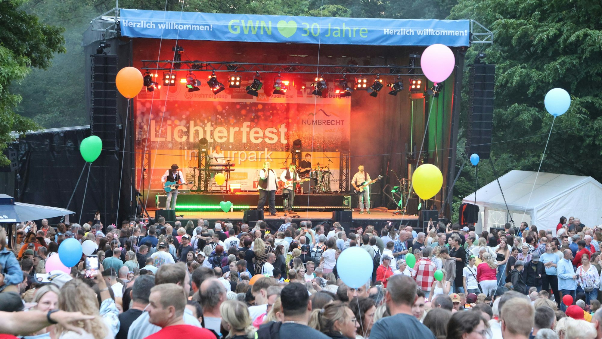 Eine große Menge vor einer Openair-Bühne, darauf eine Band.