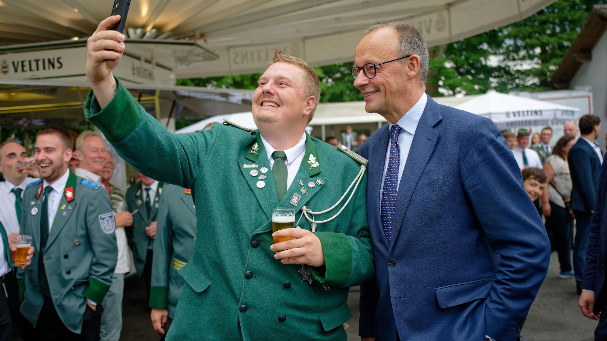 Bundeskanzler Friedrich Merz (CDU) und ein Besucher machen beim Schützenfest der St. Stephanus Schützenbruderschaft Niedereimer an der Schützenhalle ein Selfie.