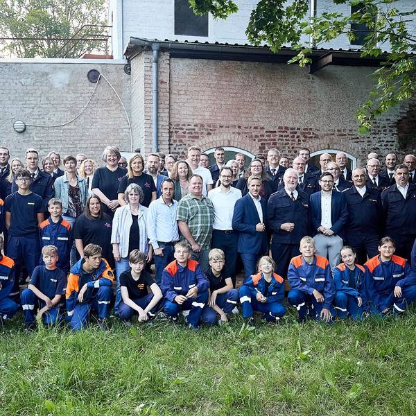Eine Gruppe Erwachsene und Kinder posiert auf einem Rasen für ein Foto.