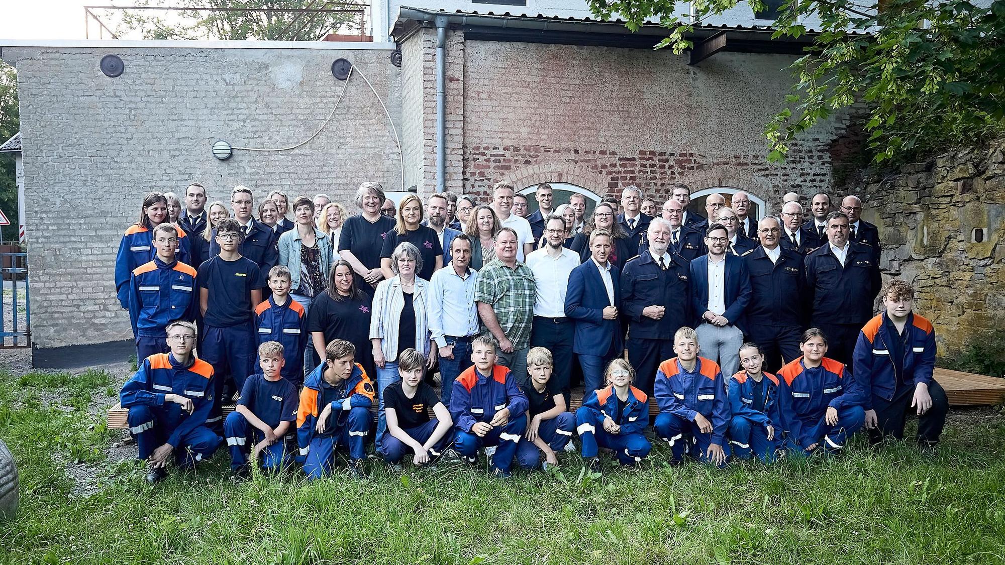 Eine Gruppe Erwachsene und Kinder posiert auf einem Rasen für ein Foto.