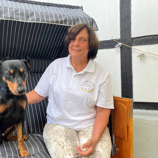 Eine Frau sitzt mit ihrem Hund zusammen in einem Strandkorb.