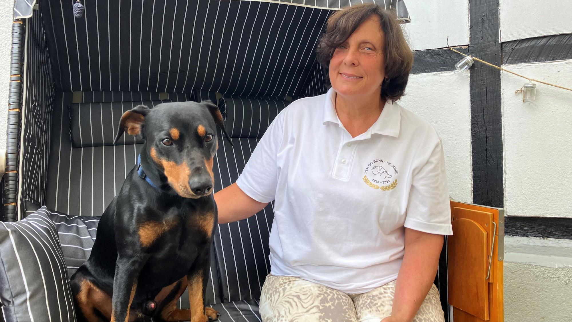 Eine Frau sitzt mit ihrem Hund zusammen in einem Strandkorb.