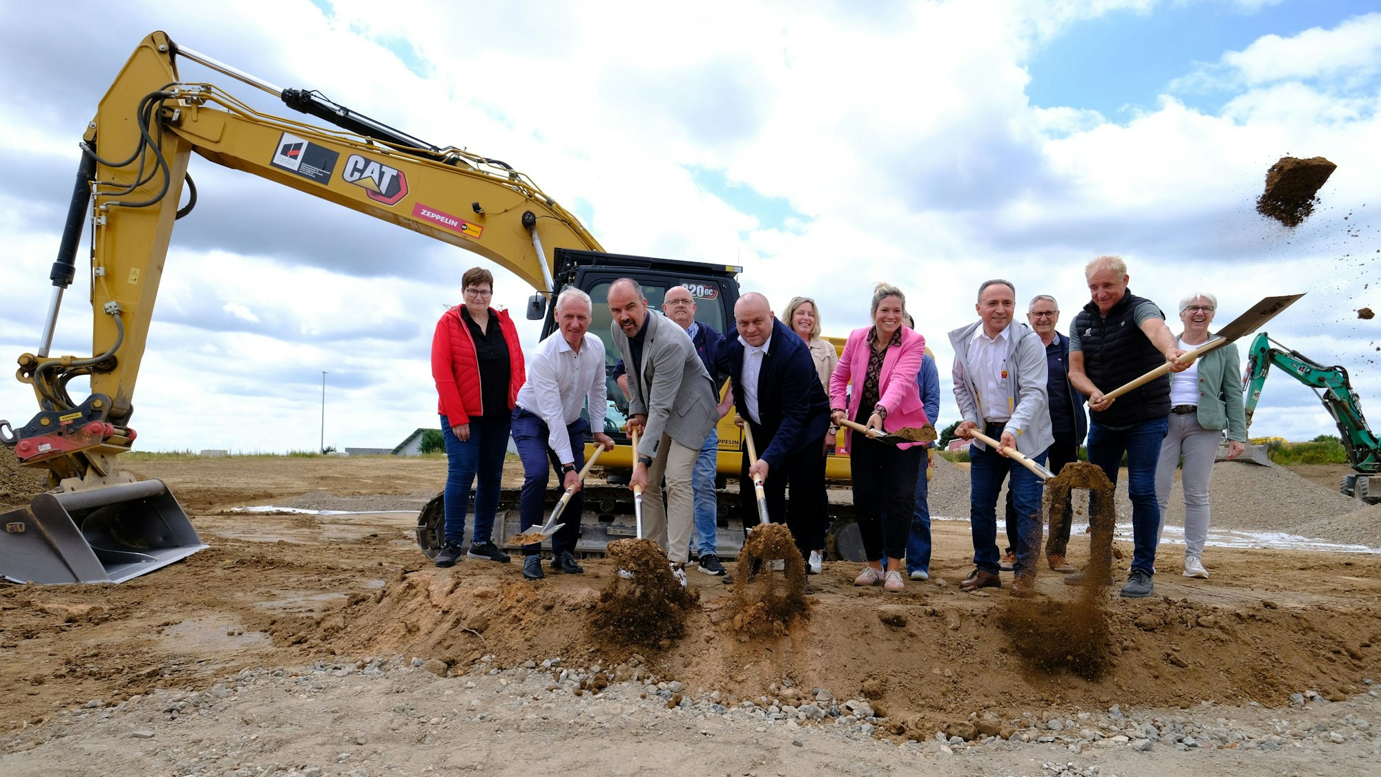 Vertreter der Gemeinde Blankenheim und des Unternehmens beim symbolischen Spatenstich zum Bau eines McDonald's-Restaurants in Blankenheim. Im Hintergrund steht ein Bagger.