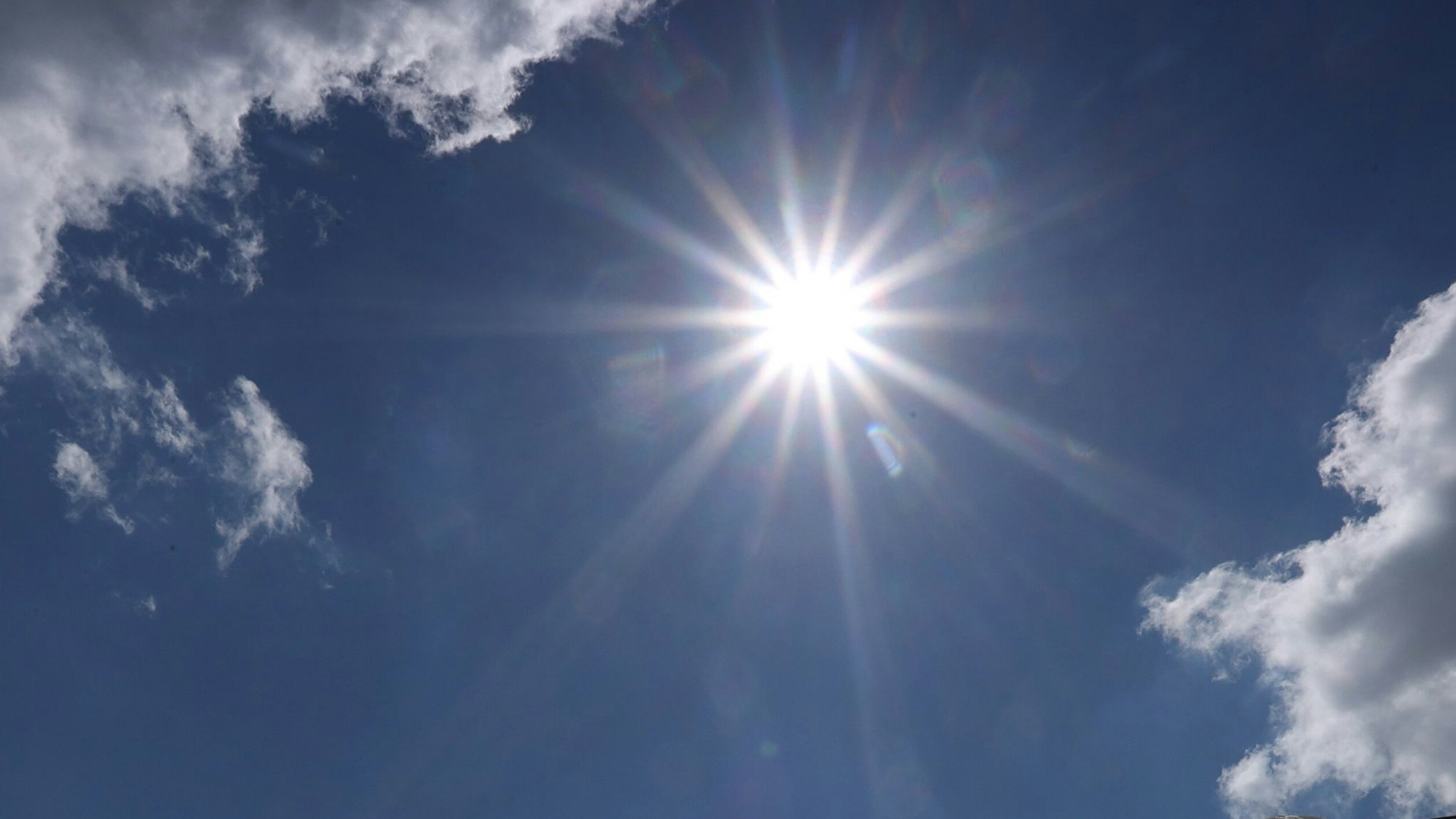 Die Sonne lugt zwischen zwei Wolken hervor.