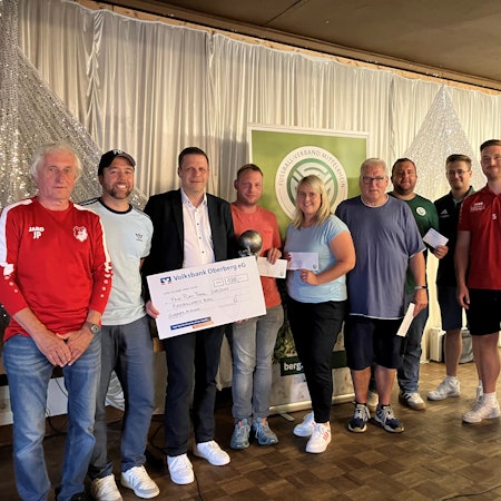 Ein Gruppenfoto verschiedener Vertreter von Fußballvereinen und einem Mitarbeiter der Volksbank, der einen Scheck in der Hand hält.