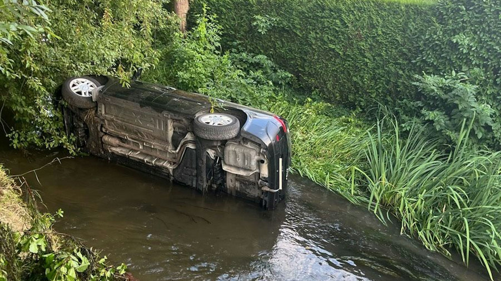 Das Auto liegt seitlich in der Erft.
