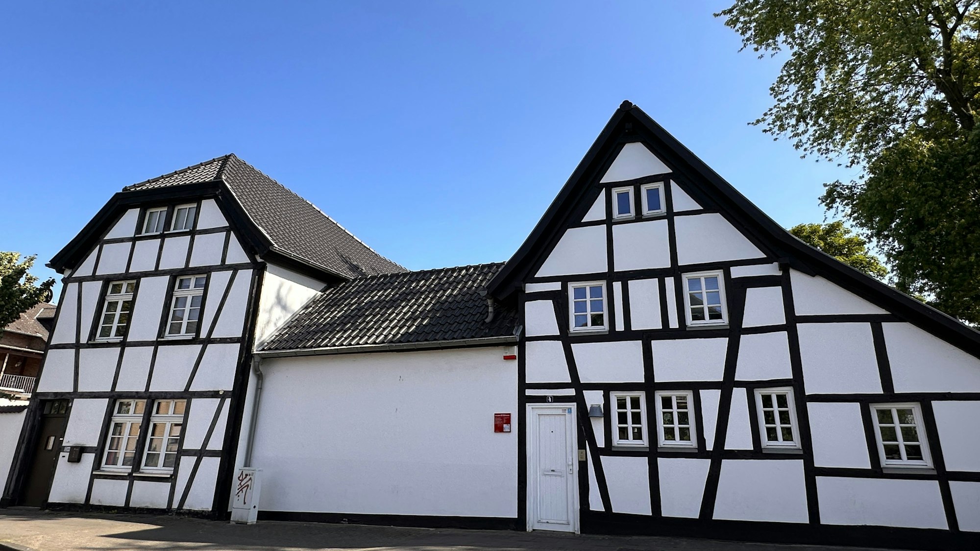 Zu sehen ist ein schwarz-weißes Fachwerkhaus in Alt Meschenich.