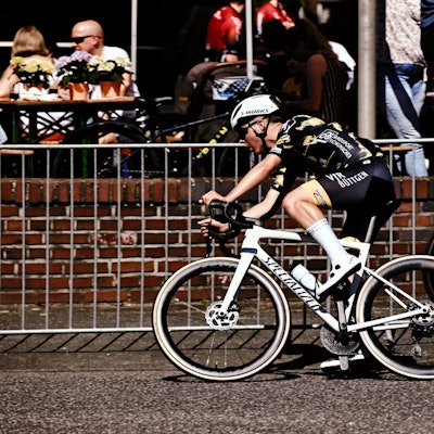 Mika Lohmar fährt auf einem weißen Rennrad an einer Absperrung vorbei.