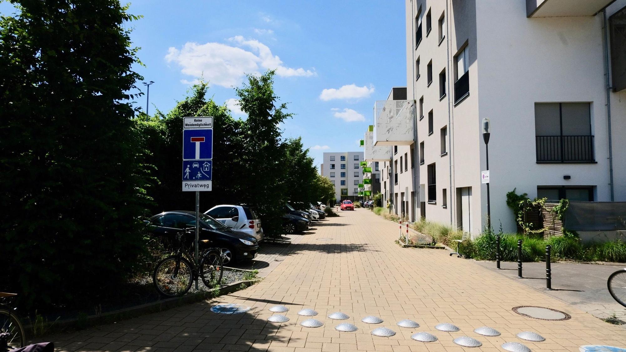 Ein Sackgassenschild steht am Beginn eines Weges, der durch Wohnblocks führt.