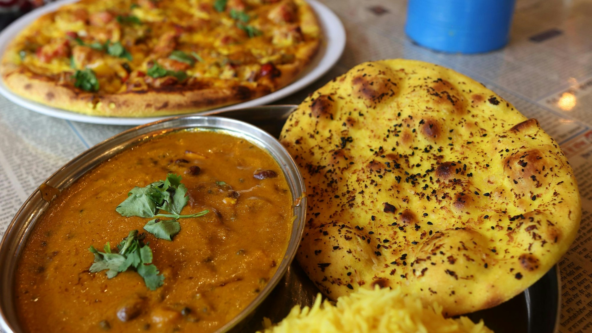 Naanizza heißt die Kreation, bei der das Curry auf Naanbrot in Pizzaform serviert wird. Es ist aber auch mit Reis und separatem Brot zu haben.