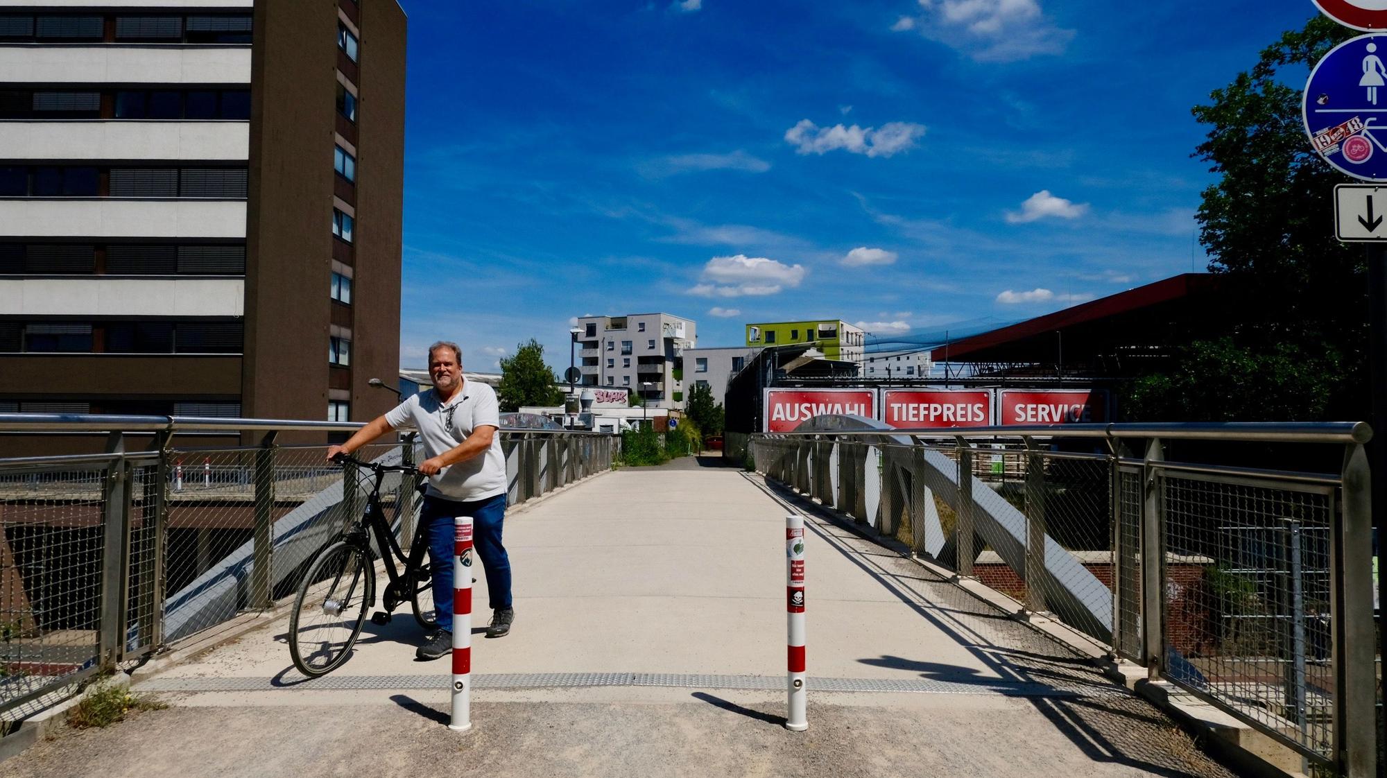 Ein Mann schiebt sein Fahrrad über eine Fuß- und Radverkehrsbrücke.