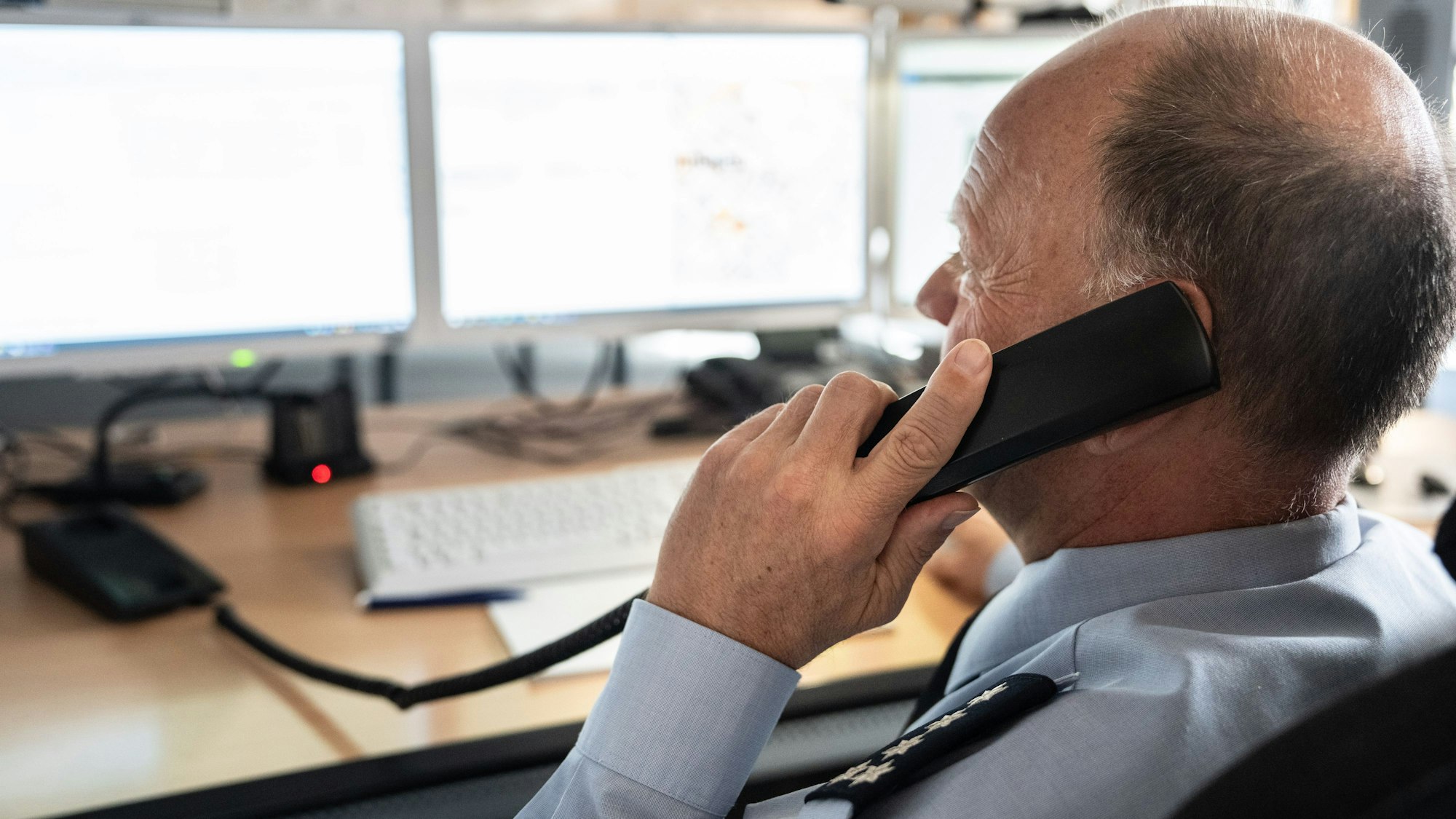 Ein Polizist telefoniert in einer Leitstelle.