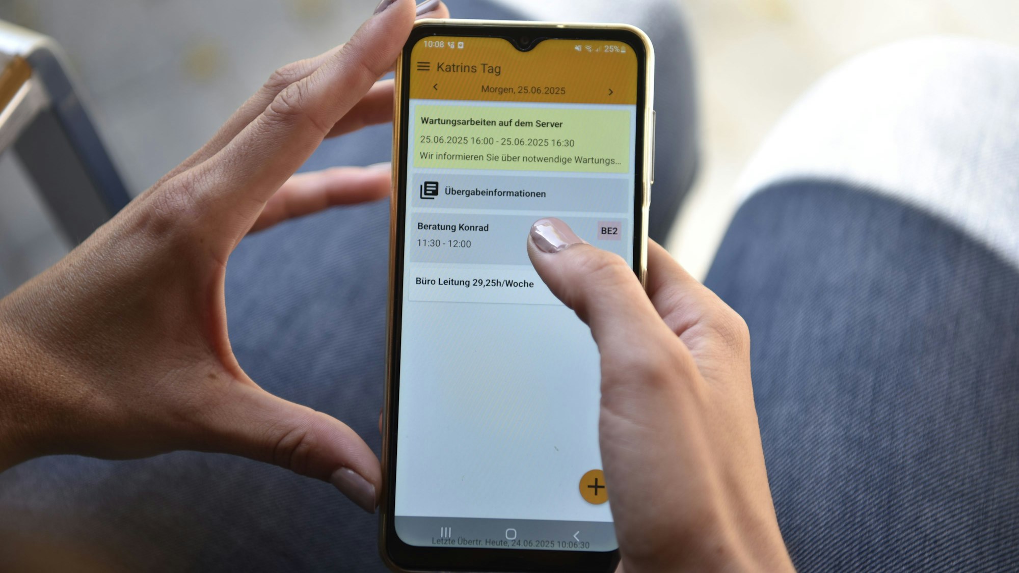 Der Blick geht auf das Display eines Smartphones, das eine Frau in den Händen hält.