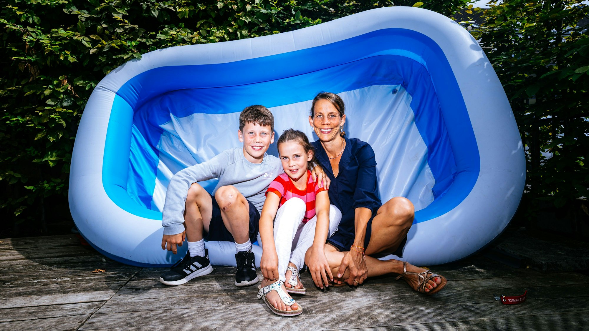 Zwei Kinder und ihre Mutter in einem leeren Schwimmbecken.