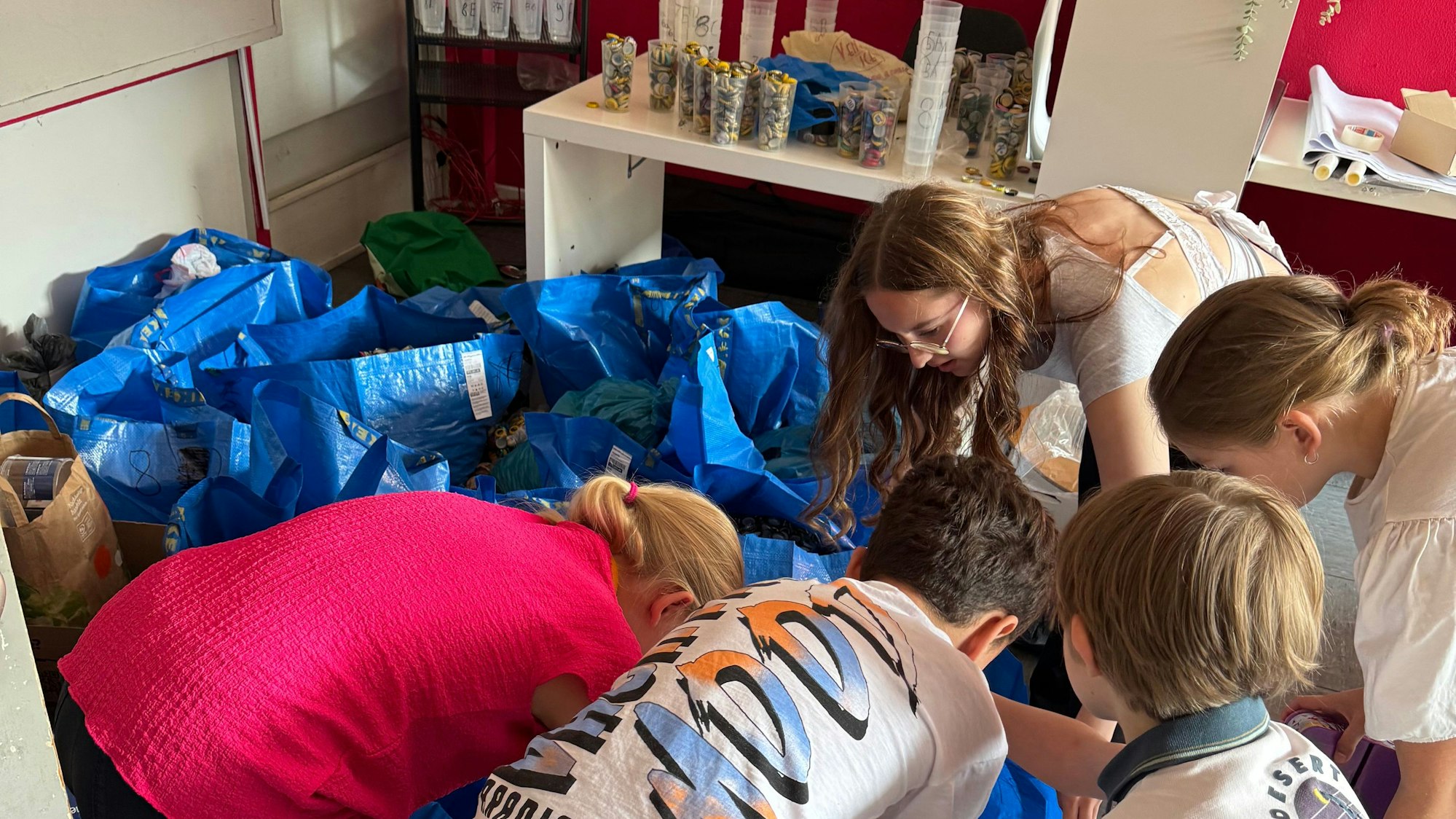 Auf dem Bild sind Kinder zu sehen, die Kronkorken in große blaue Säcke sortieren.