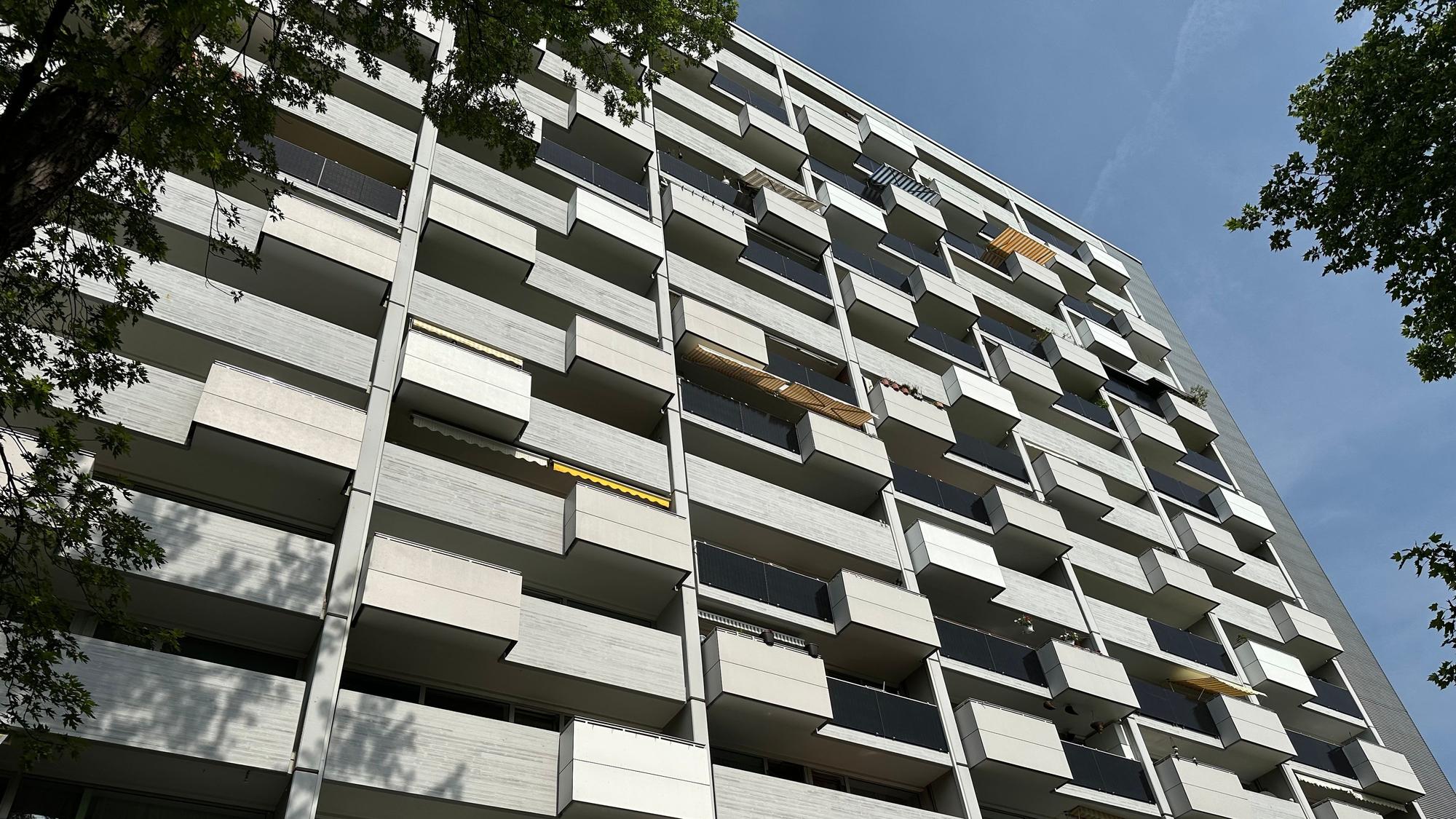 Die Fassade eines Hochhauses ist zu sehen, an vielen Balkonen sind Solarmodule angebracht.