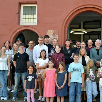 Eine Gruppe Kinder und Erwachsene steht vor einem Gebäude.