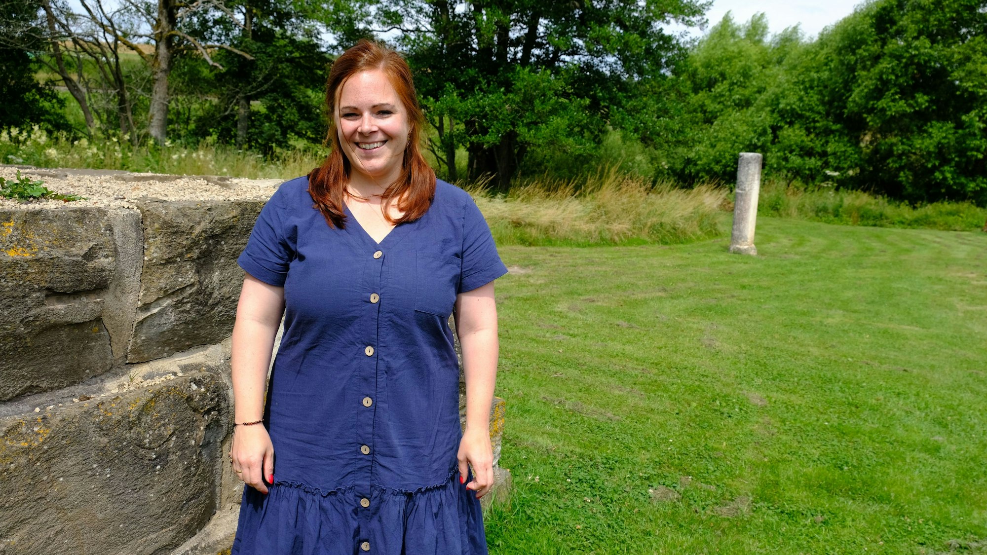 Die Archäologin Linda Lorbach am römischen Kleinkastell am Steinrütsch bei Nettersheim; sie trägt ein blaues Kleid.