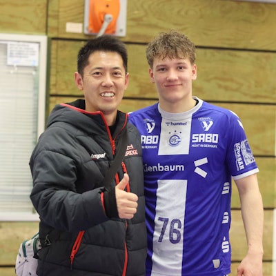 Ein Handballspieler und ein Trainer stehen zusammen.