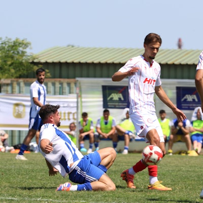 Der Spieler des SC Wißkirchen grätscht im Mittelfeld nach dem Ball, vor ihm zwei Spieler von Fortuna Köln.
