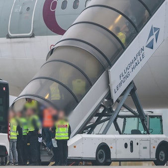 Menschen besteigen ein Flugzeug der Qatar Airways, vor dem Beamte der Bundespolizei stehen, auf dem Vorfeld am Flughafen Leipzig/Halle.