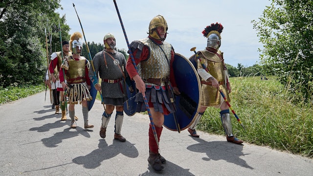 Als Römer verkleidete Männer gehen einen Weg entlang.