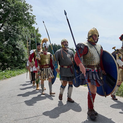 Als Römer verkleidete Männer gehen einen Weg entlang.