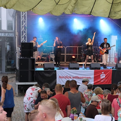 Eine Rockband auf der Bühne vor Publikum.