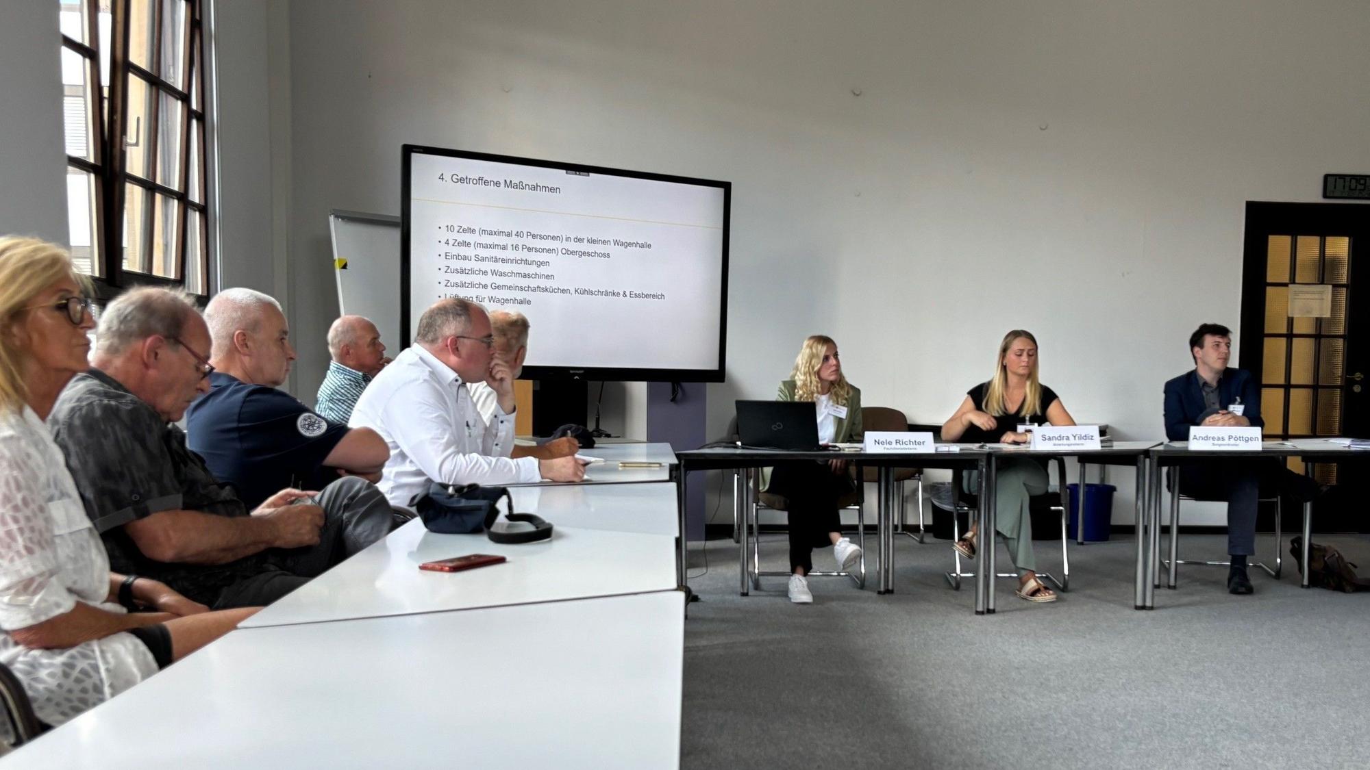 Auf dem Bild sind Personen an Tischen im Rathaus zu sehen, die eine Infoveranstaltung besuchen.