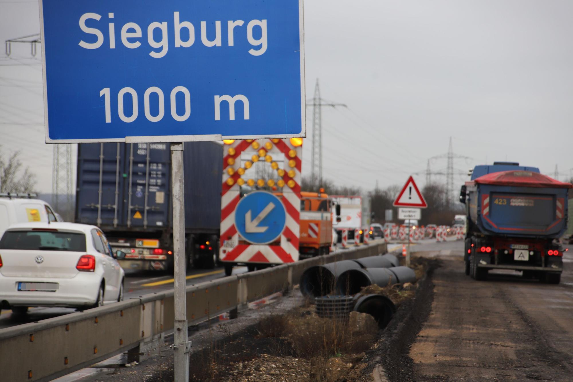 Autos und Lastwagen an einer Autobahnbaustelle; der Verkehr stockt.
