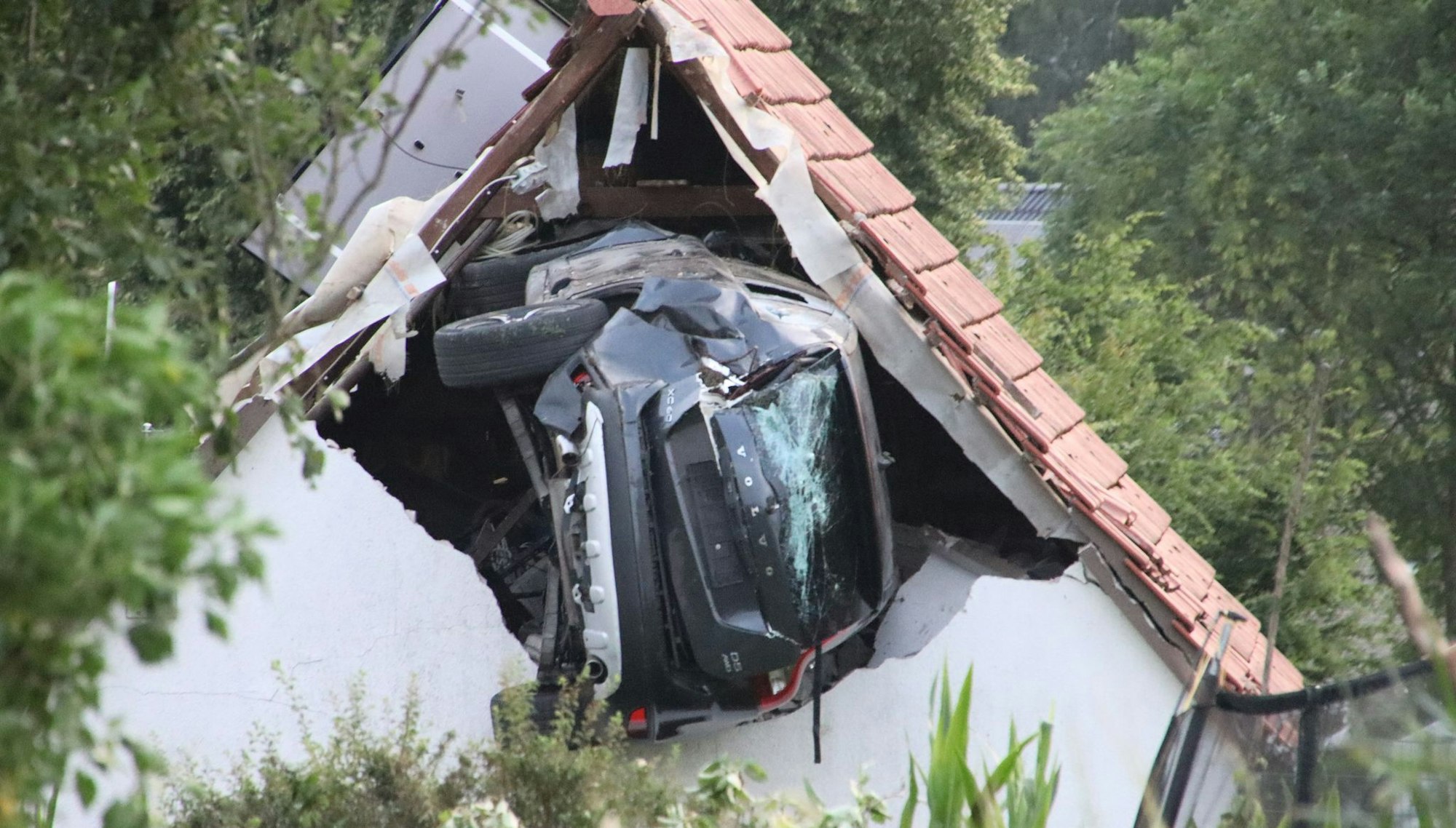 Das Auto liegt nach einem kurzen Flug seitlich in der Mauer einer Scheune.