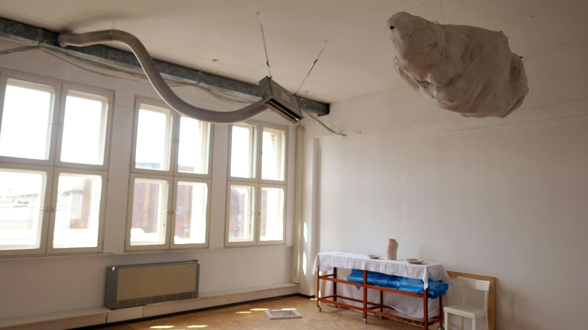 Ein Raum, in dem ein Lüftungsschlauch wie eine Schlange aus der Wand kommt.