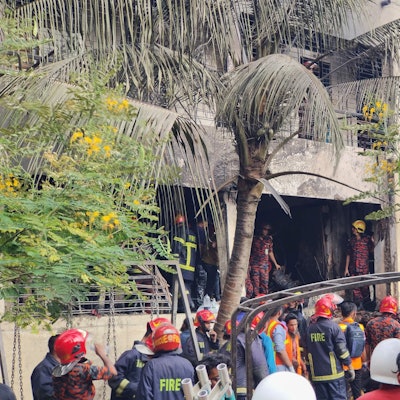 Feuerwehrleute untersuchen das Wrack eines Trainingsflugzeugs der Bangladesh Air Force, das auf ein Schulgelände abgestürzt ist.