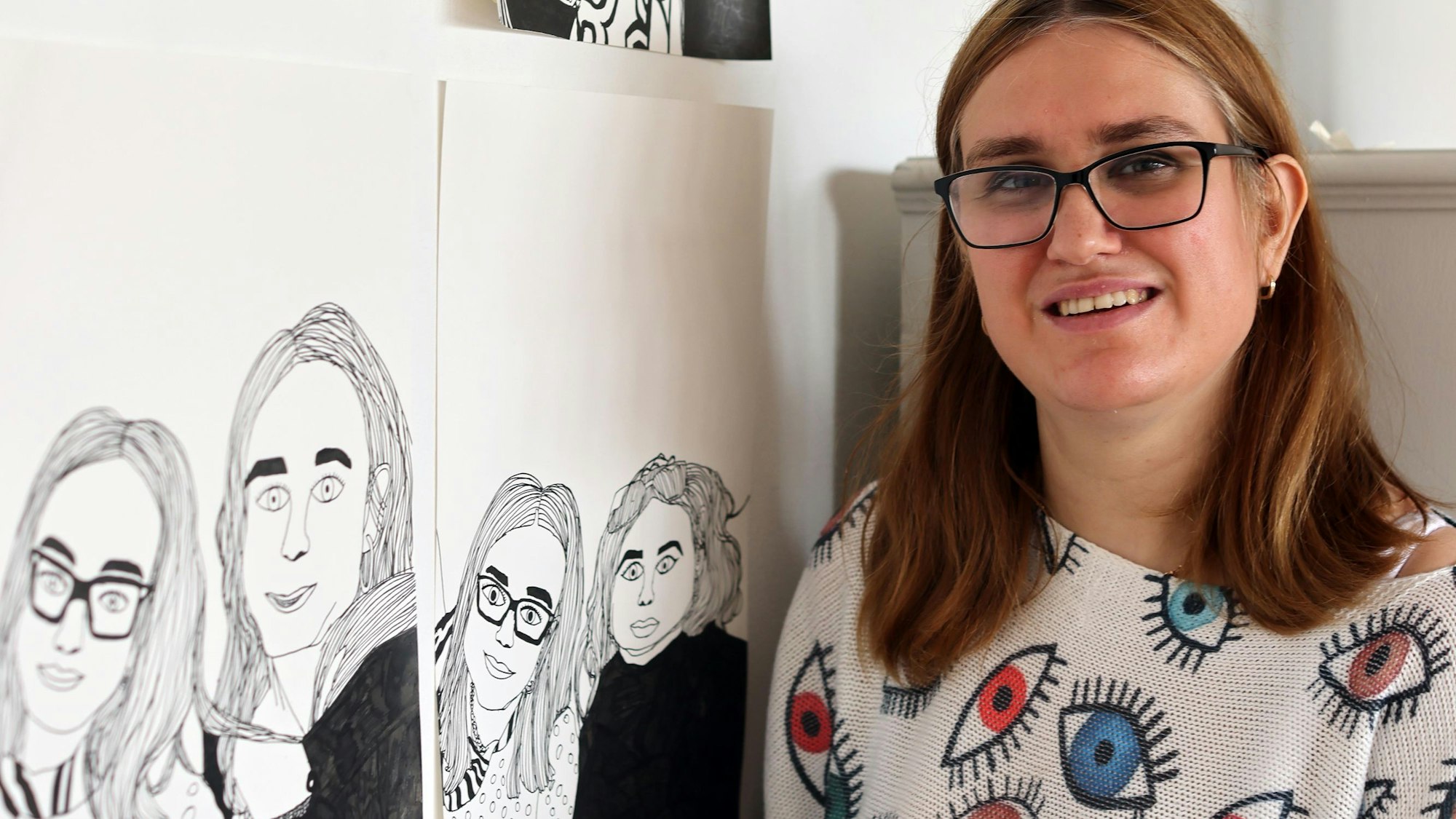 Eine junge Frau neben Schwarz-Weiß-Zeichnungen.