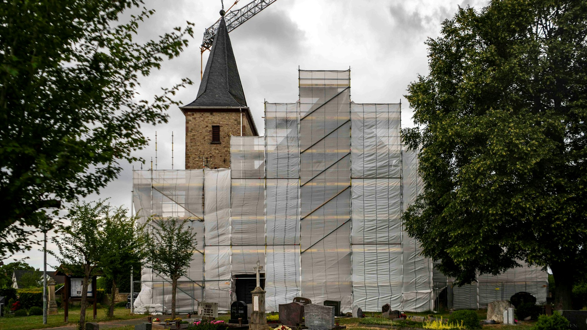 Die Kirche in Lövenich wird seit Jahren saniert. Das Haupthaus ist eingerüstet und mit Planen verhängt.