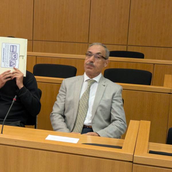 Der Angeklagte hält sich in einem Gerichtssaal in Aachen einen Aktendeckel vors Gesicht.