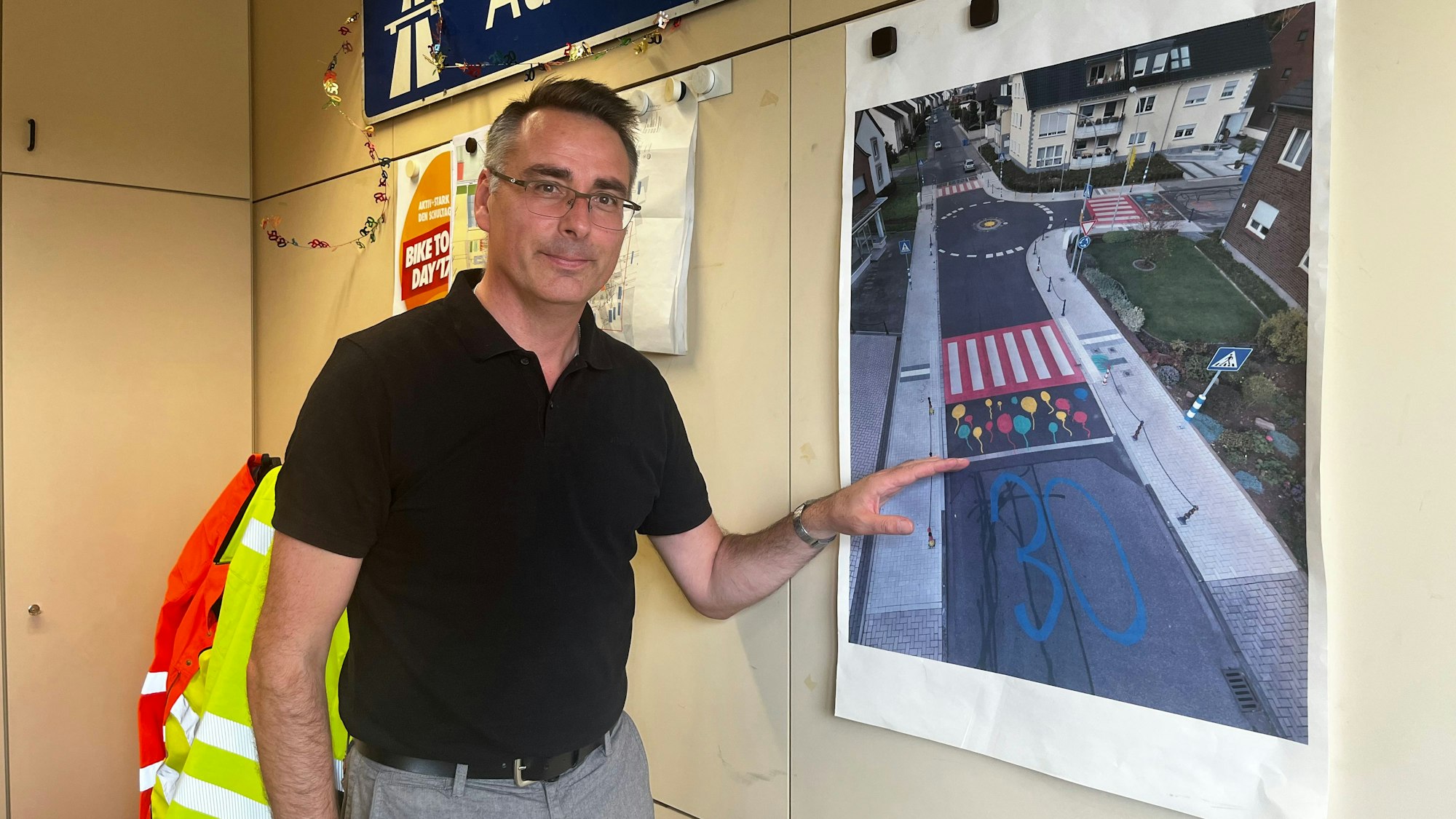 Das Foto zeigt einen Mann, der auf ein Plakat zeigt.