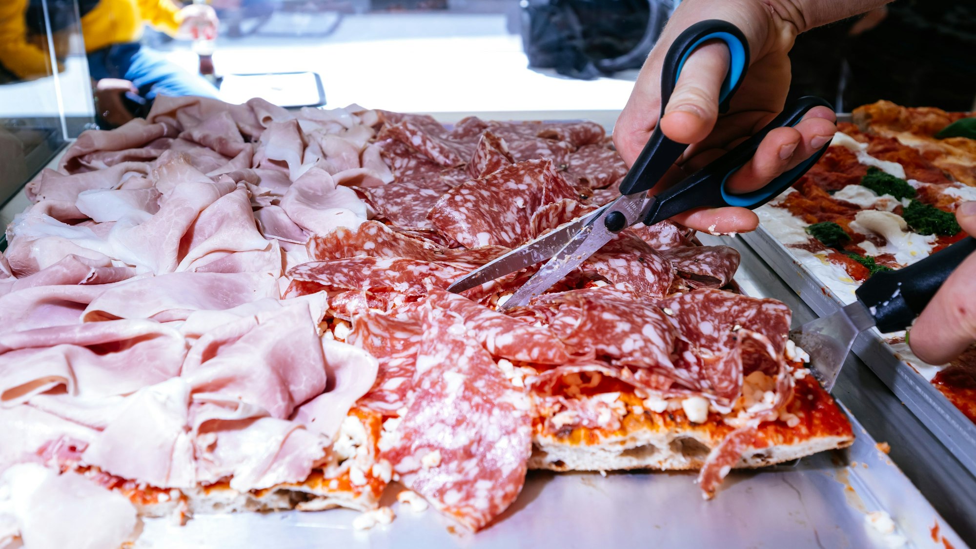 Üppig belegt: Mit der Schere wird die Pizza in eckige Stücke geschnitten.