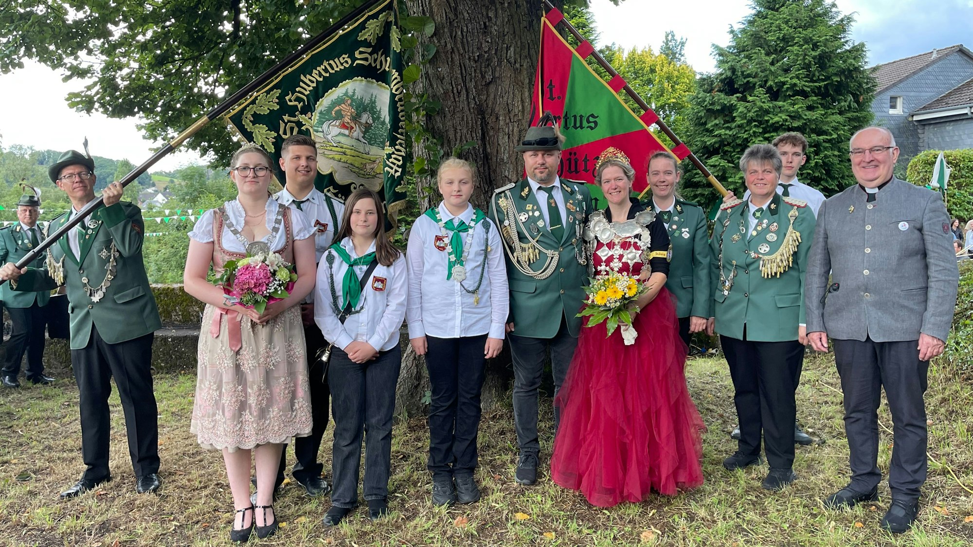 Fest gekleidete Schützen unter einer Eiche.