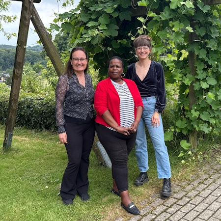 Drei Frauen lächeln in die Kamera.